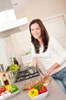 Smiling woman cutting bread in the kitchen