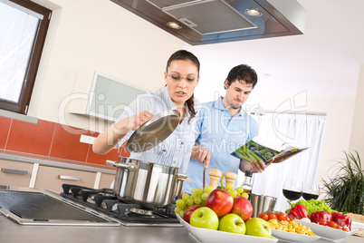 Young happy couple cook in kitchen with cookbook