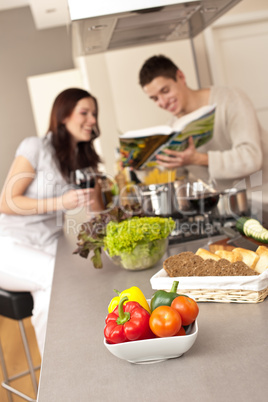 Couple in kitchen choosing recipe from cookbook