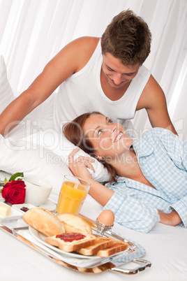 Happy man and woman having breakfast in bed together