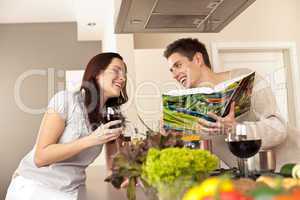 Young couple in kitchen choosing recipe from cookbook