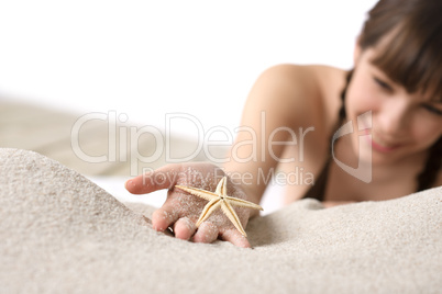 Beach - smiling woman holding starfish on sand