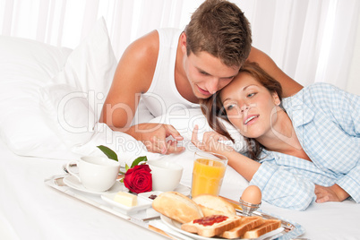 Happy man and woman having breakfast in bed together