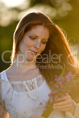 Long red hair woman in romantic sunset meadow