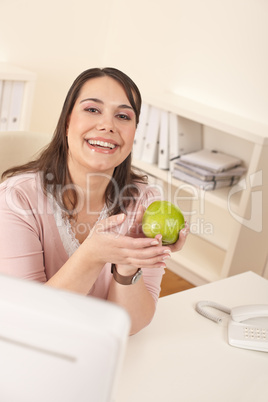 Young happy businesswoman holding apple at office