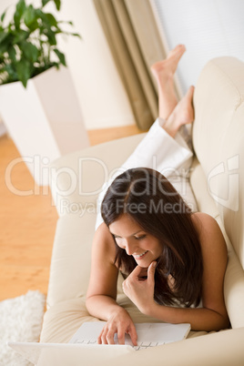 Young woman with laptop on sofa home in living room