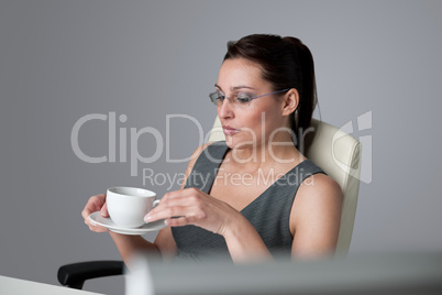 Successful business woman at office having coffee