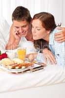 Happy man and woman having breakfast in bed together