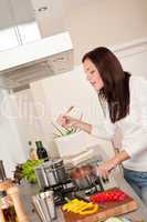Happy woman cooking tomato sauce in the kitchen