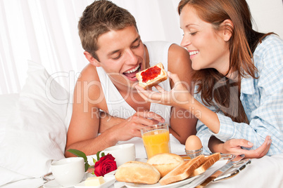 Happy man and woman having breakfast in bed together