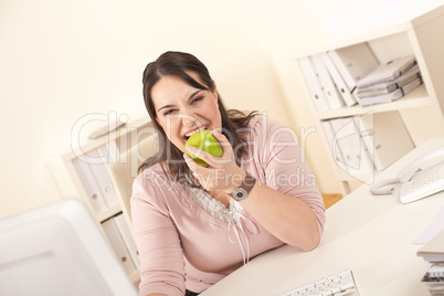 Young businesswoman biting apple at office
