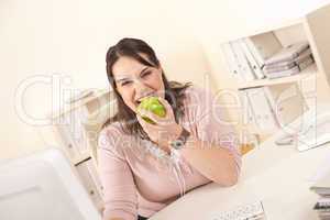 Young businesswoman biting apple at office