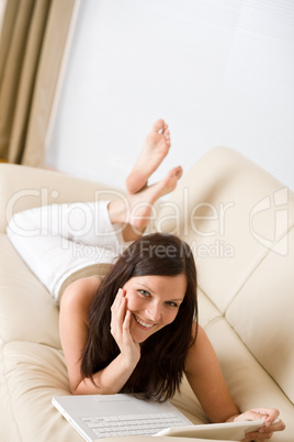 Young woman with laptop on sofa home in living room