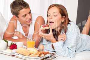 Happy man and woman having breakfast in bed together