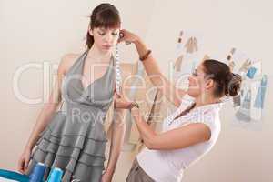 Female fashion designer measuring model for fitting