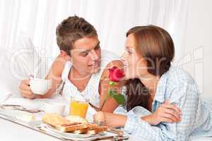 Happy man and woman having breakfast in bed together