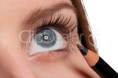 Close-up of blue eye, woman applying black pencil