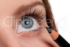 Close-up of blue eye, woman applying black pencil