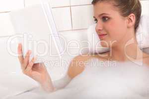 Body care series - Young woman reading book in the bathtub