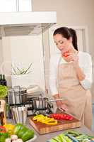 Happy woman biting red pepper in modern kitchen