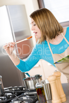 Cooking - Young woman tasting tomato sauce in kitchen