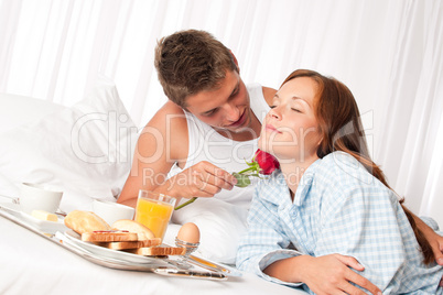 Happy man and woman having breakfast in bed together