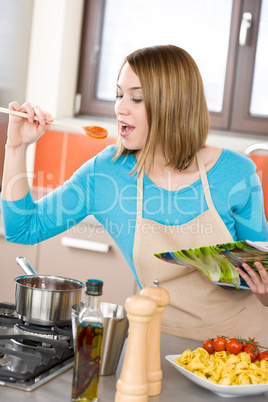 Cooking - Young woman tasting Italian tomato sauce