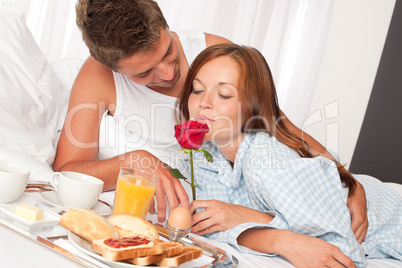 Happy man and woman having breakfast in bed together