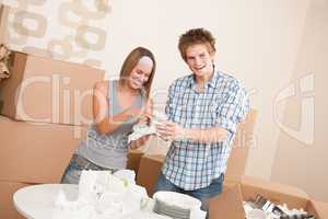 Moving house: Young couple unpacking kitchen dishes
