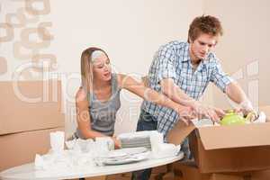 Moving house: Young couple unpacking kitchen dishes