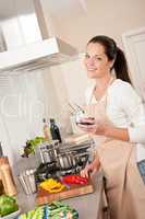 Woman with glass of red wine in the kitchen