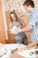 Moving house: Young couple unpacking kitchen dishes