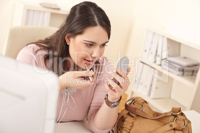 Young businesswoman applying lipstick at office