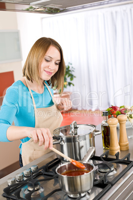 Cooking - Happy woman by stove in kitchen with pots and pans