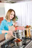 Cooking - Happy woman by stove in kitchen with pots and pans