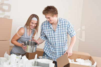 Moving house: Young couple unpacking kitchen dishes