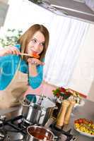 Cooking - Woman tasting Italian tomato sauce in modern kitchen