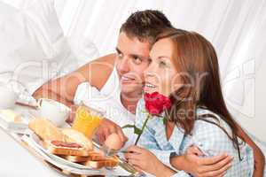 Happy man and woman having breakfast in bed together