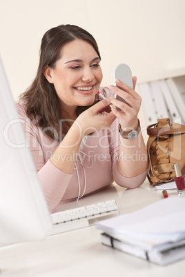 Young businesswoman applying lipstick at office