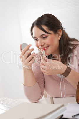 Young executive woman applying lipstick at office