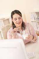 Young businesswoman eating yogurt at office