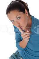 Young woman with finger on lips on white background