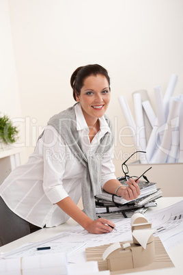 Smiling female architect with plans at the office