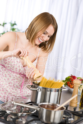 Smiling woman cooking spaghetti and tomato sauce