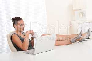 Attractive businesswoman having coffee and feet on table