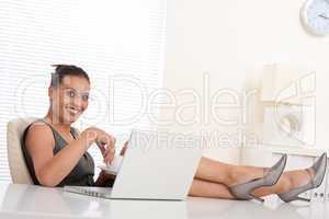 Attractive businesswoman having coffee and feet on table