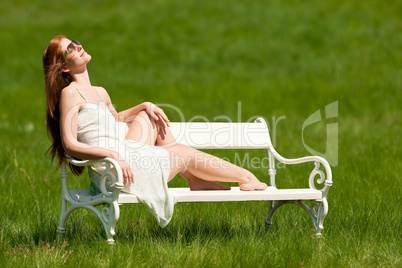 Red hair woman sitting on white bench in spring