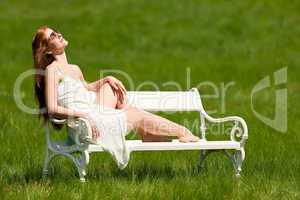 Red hair woman sitting on white bench in spring