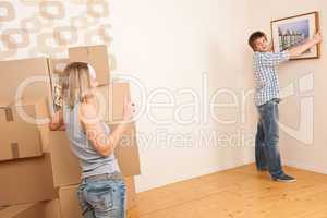 Moving house: Couple hanging picture on wall