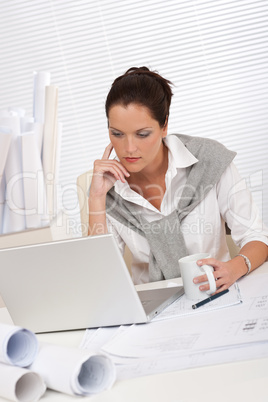 Female architect with laptop and coffee sitting